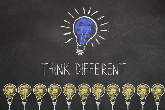 Gl&uuml;hbirnen und Schriftzug "think different" mit eine Idee Gl&uuml;hbirne auf Kreidetafel 