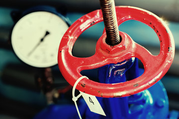 red valve and pressure sensor on the gas supply or heating pipe. Industrial background with...