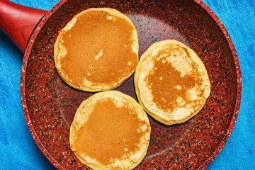 Ruddy and lush pancakes on a stone pan. Granite pan with baking on blue background