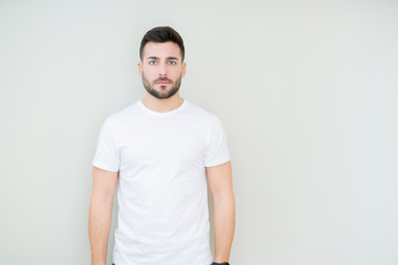 Young handsome man wearing casual white t-shirt over isolated background Relaxed with serious expression on face. Simple and natural looking at the camera.
