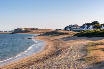 French landscape - Bretagne. A beautiful beach with rocks and fortress in the background at sunrise.