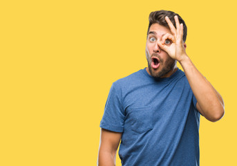 Obraz premium Young handsome man over isolated background doing ok gesture shocked with surprised face, eye looking through fingers. Unbelieving expression.