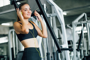 Fototapeta na wymiar Active girl using smartphone in fitness gym. Young woman workout in gym healthy lifestyle. Young woman using phone in gym. Change for health concept.