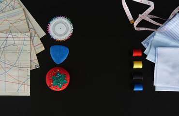 elementos para coser, tijeras, agujas, hilo de colores, centímetro, en un fondo negro
