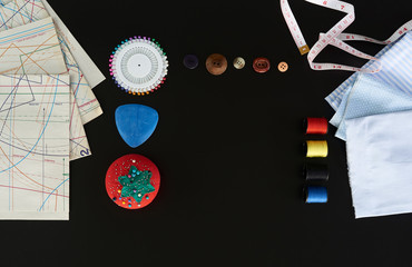 elementos para coser, tijeras, agujas, hilo de colores, centímetro, en un fondo negro