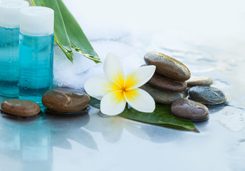 Spa or wellness setting with flower, stones, towel and cream tube.