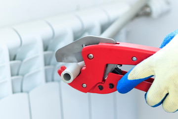 man with red scissors cut pipes for heating, or water. polypropylene mounting system