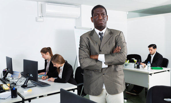 African American businessman standing at office on background with working colleagues