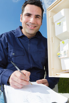 electrician smiling while drawing information of fuse box