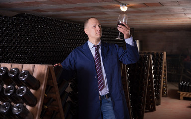 Winemaker degusting red wine in wine cellar