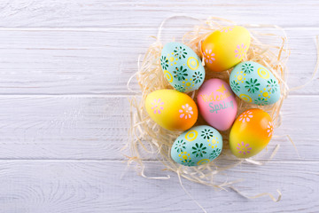 Easter holiday background with eggs. Close up of colorful painted chicken eggs in the nest