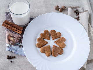 The glass of the milk with handmade's cakes on the plate near serviettes with  allspices and other spices on the natural tablecloth This picture have made by middleformat camera