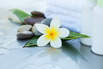Fototapeta na wymiar Spa setting with tropical flowers, towel and cream tube. Body care and spa concept