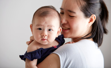 Closeup Asian baby leaning on mother's shoulder
