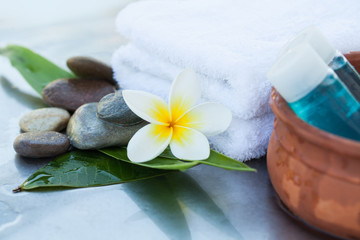 Fototapeta na wymiar Spa setting with tropical flower, bowl with oil tube and towel. Body care and spa concept