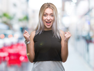 Young blonde woman over isolated background celebrating surprised and amazed for success with arms raised and open eyes. Winner concept.