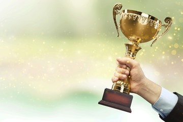 Hand of kid holding champion cup on glossy background