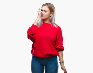 Young blonde woman wearing winter sweater over isolated background smelling something stinky and...