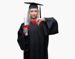 Young blonde woman wearing graduate uniform holding degree over isolated background with angry...