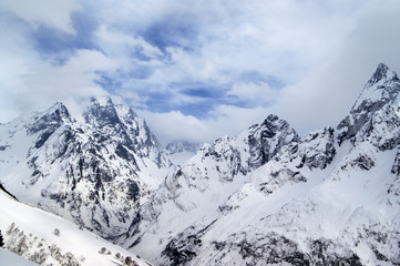 Fototapeta na wymiar Gray high mountain peaks covered with ice and clouds at winter