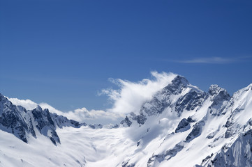Fototapeta na wymiar Winter snowy mountains in clouds and beautiful blue sky