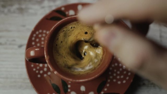 Echando az&uacute;car en el caf&eacute; y removiendo con una cucharilla