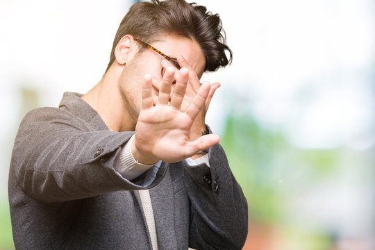Young business man wearing glasses over isolated background covering eyes with hands and doing stop gesture with sad and fear expression. Embarrassed and negative concept.