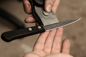 The master checks the sharpening of a knife from Damascus steel.