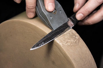 Sharpening a Damascus steel knife on the water stone of a grinding machine.