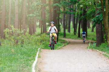 Child teenager in white t shirt and yellow shorts on  bicycle ride in  forest at spring or summer. Happy smiling Boy cycling outdoors. Active lifestyle, hobby