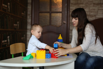 Obraz na płótnie Canvas Toddler with mother plays with plastic constructor