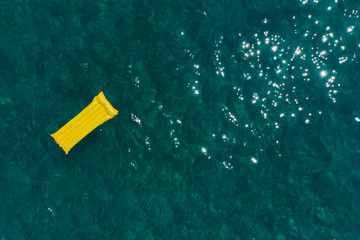 summer vacation concept. yellow inflatable mattress in blue azure sea water.