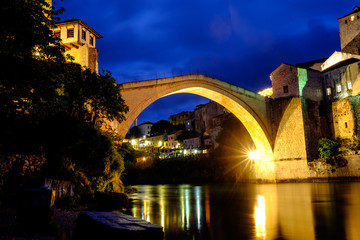 Fototapeta na wymiar The Stari Most bridge over the river Neretva in Mostar, standing in its full glory against the blue night skies