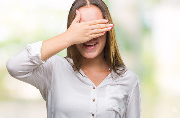 Young caucasian beautiful business woman wearing glasses over isolated background smiling and laughing with hand on face covering eyes for surprise. Blind concept.