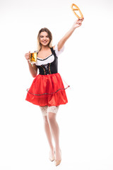 Young Oktoberfest woman wearing a traditional Bavarian dress dirndl posing with a pretzel and beer mug in hands on white background.