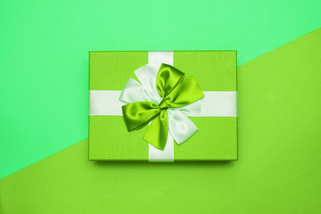 Real box with white and green bow and ribbon top view on Valentine's day isolated on green background. Flat lay. Copy space