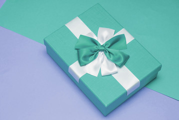 Real box with white and blue bow and ribbon top view on Valentine's day isolated on blue and purple background. Flat lay. Copy space.