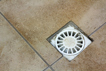 Water drain vent in kitchen, bathroom or basement ceramic tiled old vintage floor. Geometric...