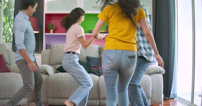 Slow motion of Young friends running and jumping on sofa then smiling and looking at camera all together at home.