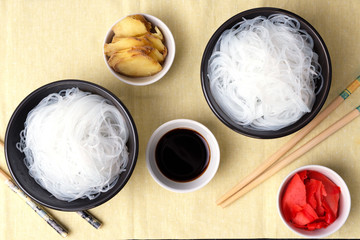 Chinese glass noodles with ingredients for cooking, vegetables and spices, ginger and soy sauce on black background top view