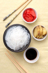 Chinese glass noodles with ingredients for cooking, vegetables and spices, ginger and soy sauce on black background top view