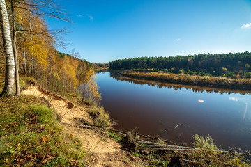 blue sky and clouds reflecting in calm water of river Gauja in latvia in autumn