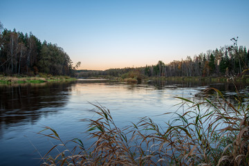 blue sky and clouds reflecting in calm water of river Gauja in latvia in autumn