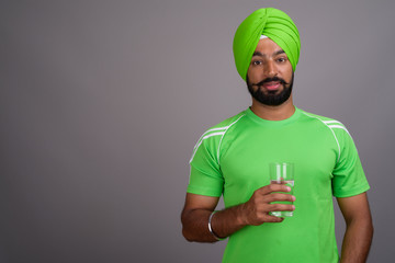 Young handsome Indian Sikh man wearing turban and green shirt