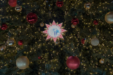 Big snowflake with painted children at the branch of Christmas tree