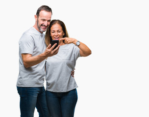 Middle age hispanic couple texting message on smartphone ver isolated background very happy pointing with hand and finger