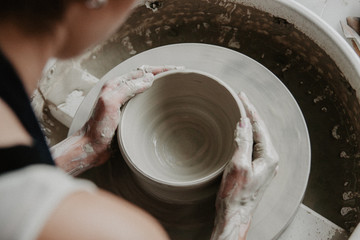 Creating a jar or vase of white clay close-up. Woman hands making clay jug.