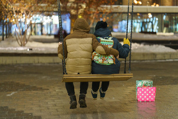 A couple is swinging on a city street, their gift bags are nearby.