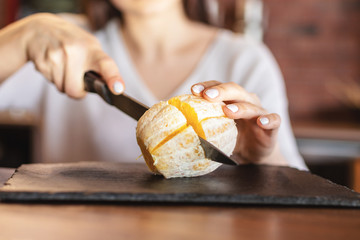 A young woman-cook slicing fruits: apple, kiwi and orange, preparing to make juice with electric...