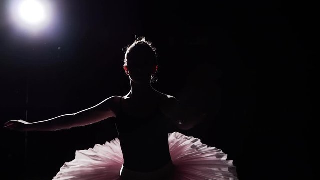 Slow motion shot of ballerina dancing in studio. Beautiful female ballet dancer on a black background. Ballerina wearing tutu and pointe shoes. Slow motion.